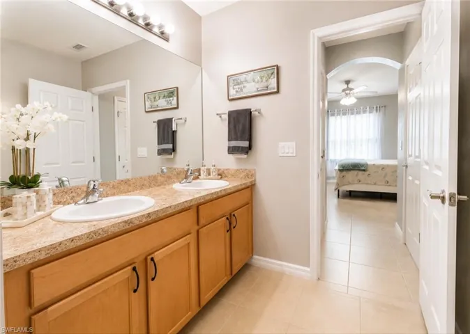 Dual vanity with integrated sinks, wood-finish cabinetry, and a full-width mirror