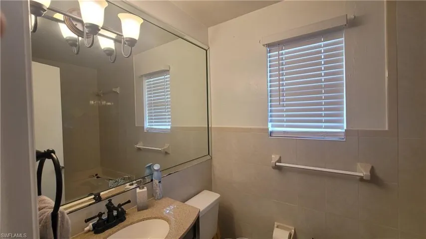 Master bathroom with tile walls, toilet, vanity, and plenty of natural light