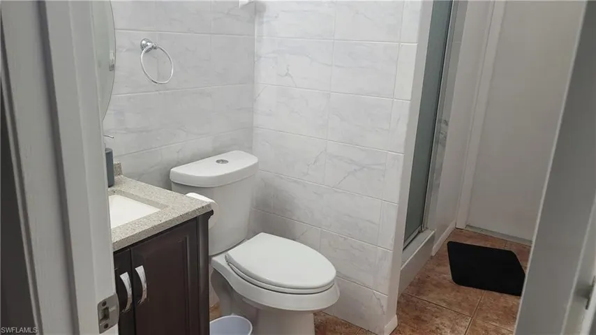 Bathroom featuring tile walls, tile patterned floors, toilet, and vanity