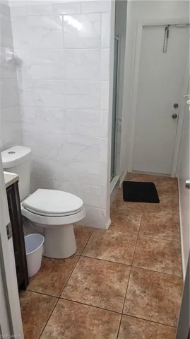 Bathroom featuring vanity, tile walls, toilet, and tile patterned floors