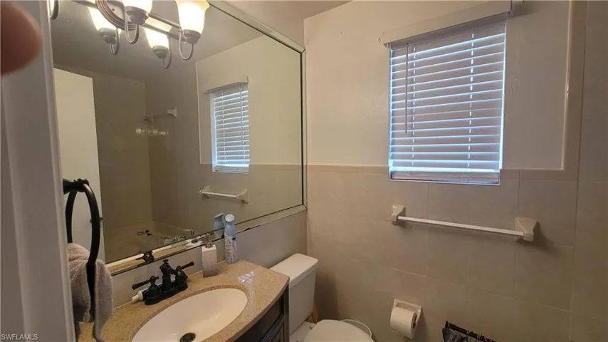 Bathroom with vanity, tile walls, and toilet