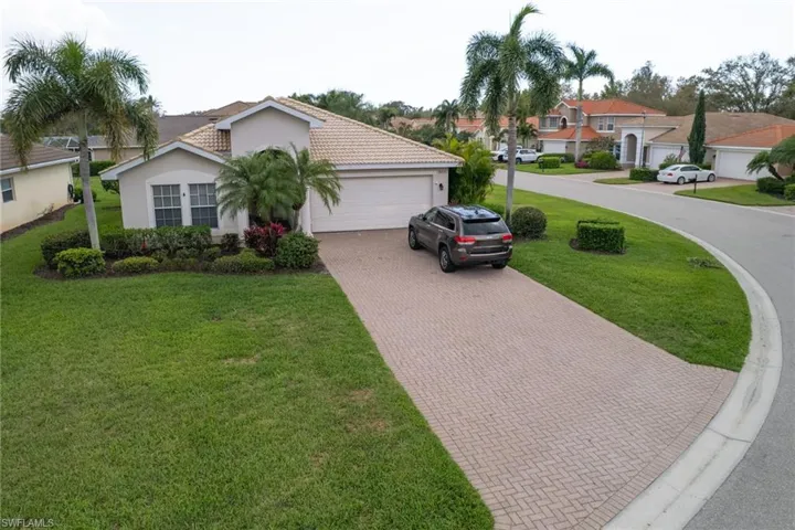 Mediterranean / spanish-style house with decorative driveway, a front lawn, an attached garage, stucco siding, and a residential view