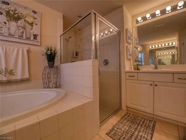 Bathroom with a stall shower, vanity, a bath, and light tile patterned flooring