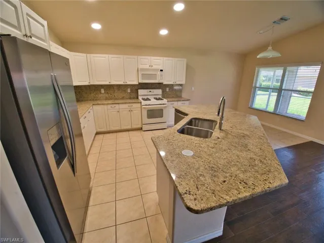 Kitchen featuring a large central island with a double stainless steel sink and a gooseneck faucet