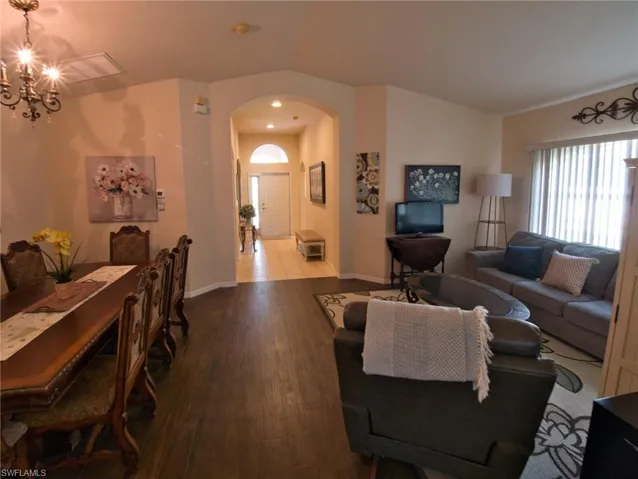 Living room featuring arched walkways, wood finished floors, hanging lights, and vaulted ceiling