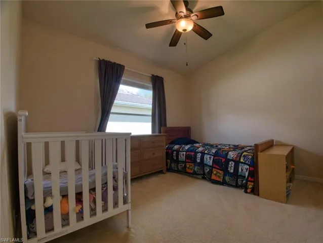 Bedroom featuring vaulted ceiling, light carpet, and a ceiling fan