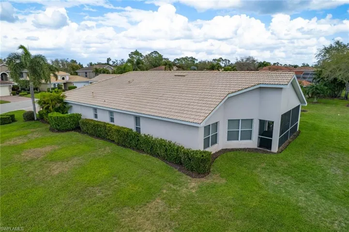 Back of property featuring a tiled roof, stucco siding, a yard, and a sunroom