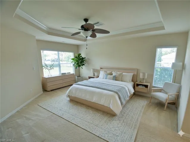Spacious room featuring a tray ceiling with crown molding and a ceiling fan