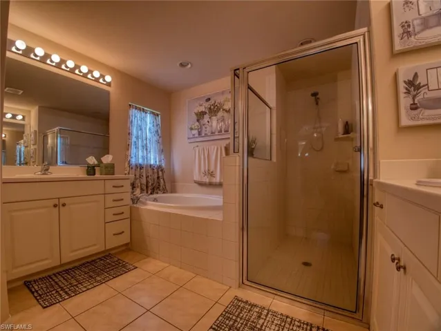 Full bath with vanity, a stall shower, a bath, and light tile patterned floors