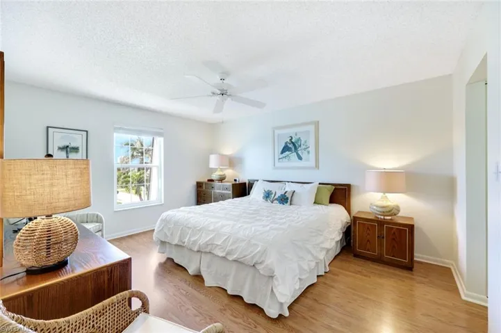 Primary bedroom featuring laminate wood floors, a textured ceiling, a ceiling fan, and a walk-in closet