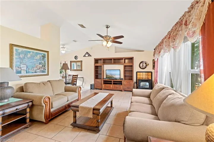 Tiled living room featuring ceiling fan and vaulted ceiling