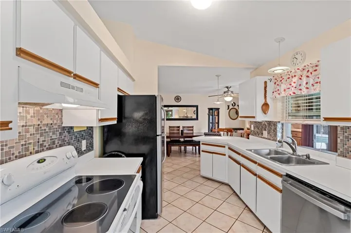 Kitchen featuring appliances with stainless steel finishes, extractor fan, sink, pendant lighting, and white cabinetry