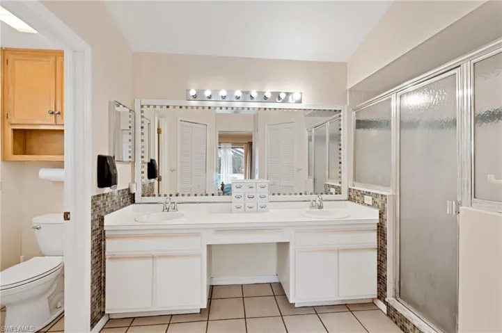 Bathroom featuring tile patterned flooring, vanity, a shower with shower door, and toilet