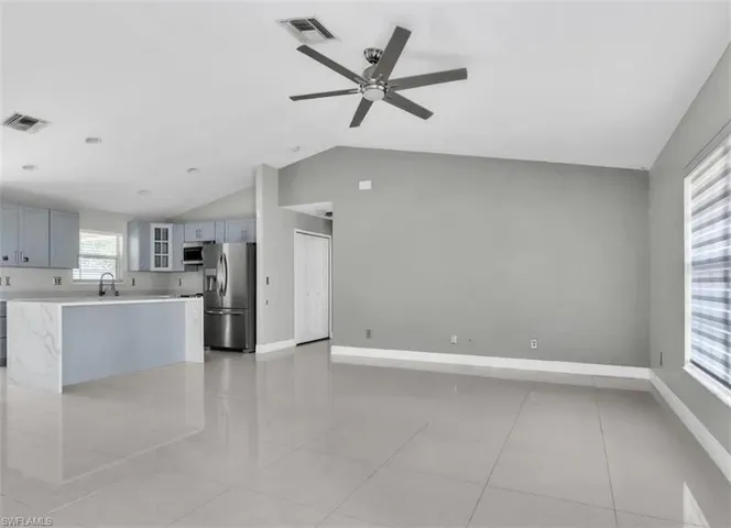Unfurnished living room with lofted ceiling, a ceiling fan, and light tile patterned floors