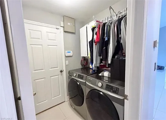 Washroom with cabinet space, washing machine and clothes dryer, and light tile patterned floors
