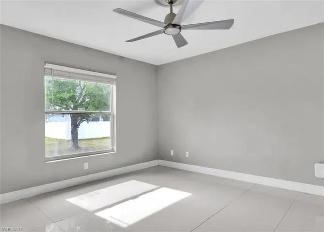 Empty room featuring a ceiling fan and light tile patterned flooring
