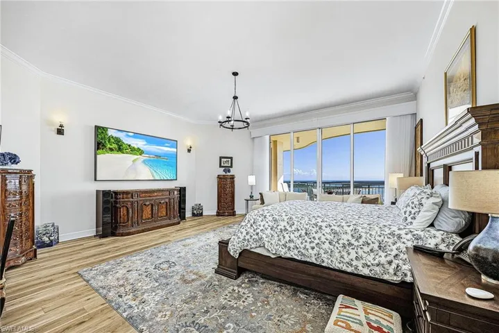 Bedroom featuring crown molding, wood finished floors, access to outside, and a chandelier