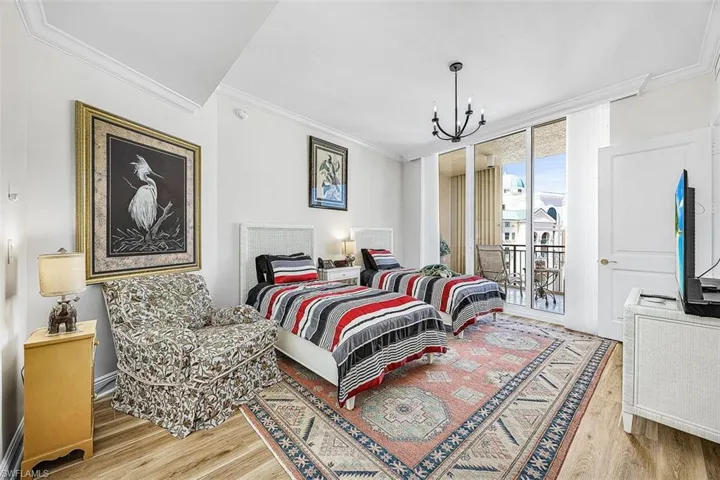 Bedroom with expansive windows, crown molding, a chandelier, light wood-style floors, and access to exterior