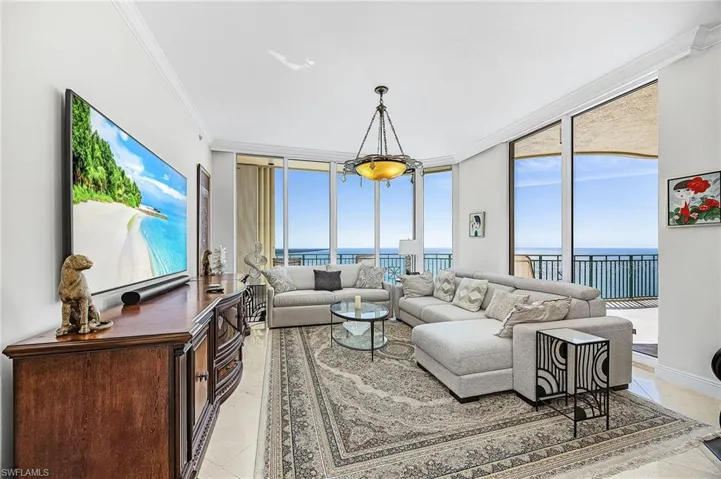 Living area featuring a water view, a wall of windows, crown molding, and light tile patterned floors