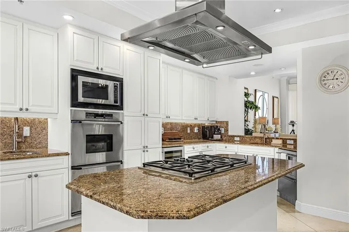 Kitchen with island range hood, dark stone counters, recessed lighting, white cabinetry, and decorative backsplash