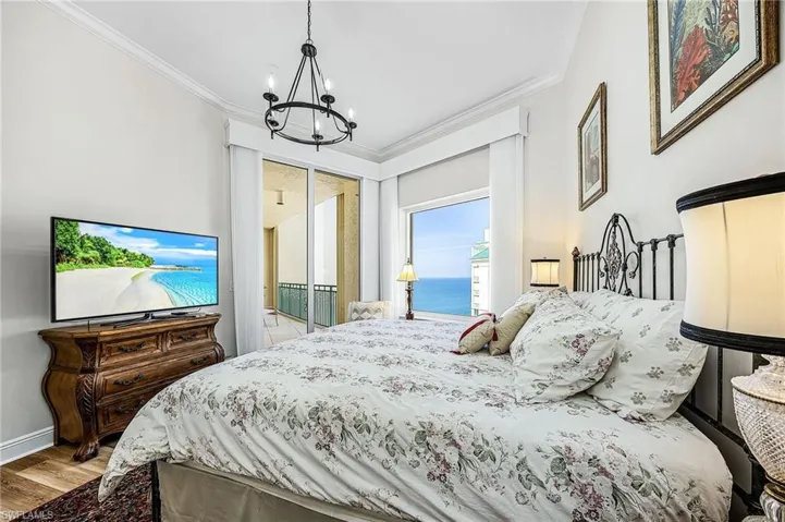 Bedroom featuring access to outside, a chandelier, a water view, light wood-style floors, and ornamental molding