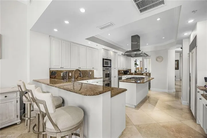Kitchen with a peninsula, a kitchen island, a breakfast bar, crown molding, and recessed lighting