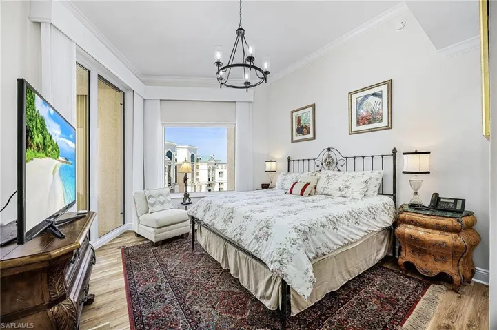 Bedroom with crown molding, a chandelier, and light wood-style floors