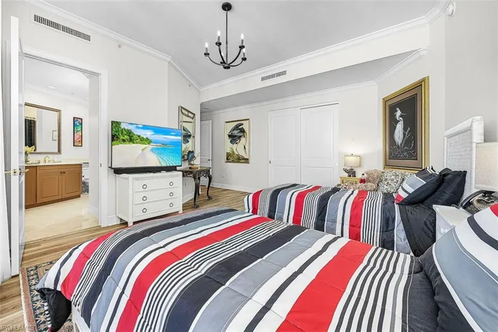 Bedroom with ornamental molding, light wood-style floors, a closet, and a chandelier