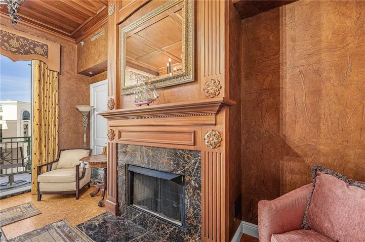 Sitting room featuring a high end fireplace, wooden ceiling, crown molding, and wood walls