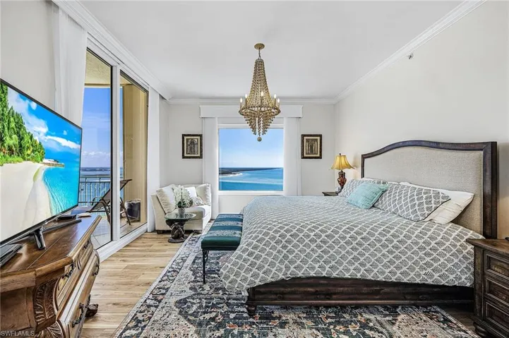 Bedroom with wood finished floors, access to exterior, a chandelier, and crown molding