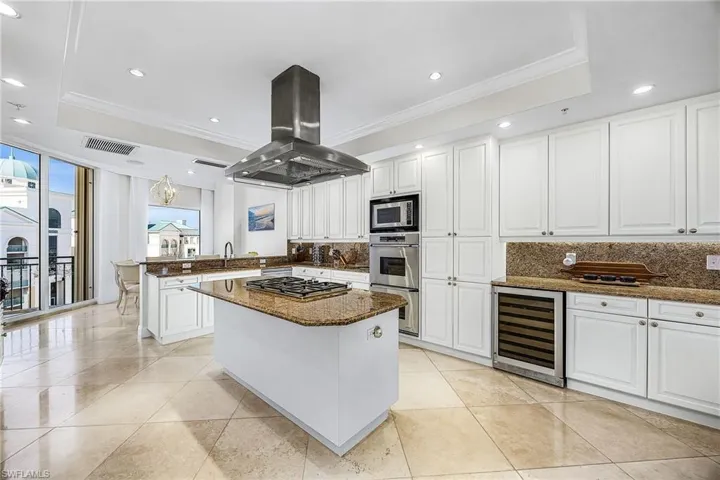 Kitchen with recessed lighting, dark stone counters, white cabinetry, a tray ceiling, and crown molding