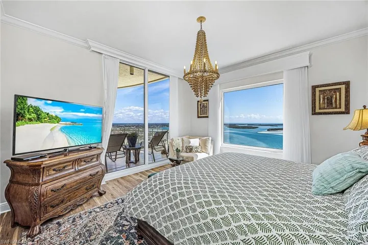 Bedroom featuring wood finished floors, ornamental molding, access to outside, a chandelier, and a water view