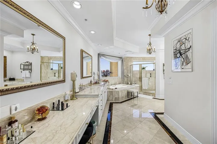 Bathroom with a chandelier, a bath, inlaid floor details, a stall shower, and ornamental molding