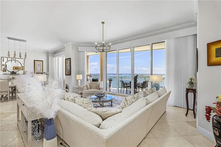 Living room with crown molding, a chandelier, and a water view