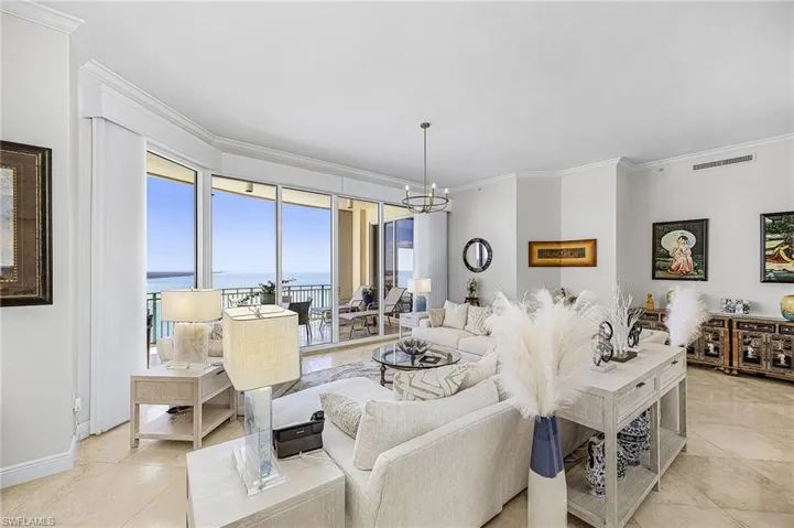 Living area with ornamental molding, a water view, a chandelier, and light tile patterned floors