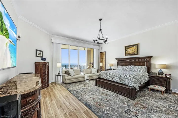 Bedroom featuring crown molding, light wood-style flooring, a chandelier, access to outside, and a water view