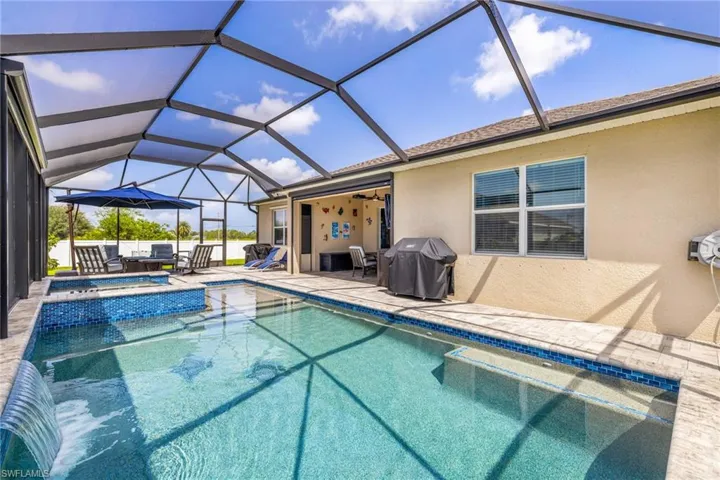 Screened lanai featuring a swimming pool, integrated spa with mosaic tile, and waterfall feature
