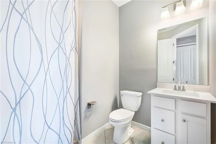 Full bathroom featuring a white vanity with integrated sink, chrome faucet, wall-mounted mirror, and a three-light fixture