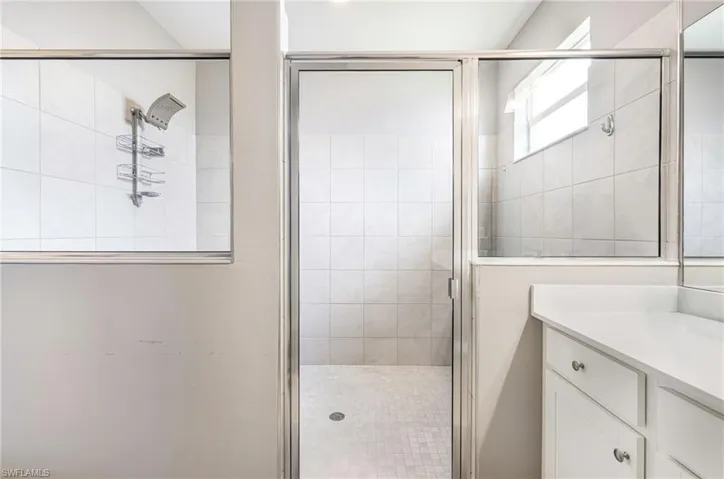 Glass-enclosed shower with subway tile walls and mosaic tile flooring