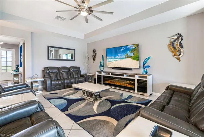 Spacious living area featuring a tray ceiling, contemporary ceiling fan, and tile flooring