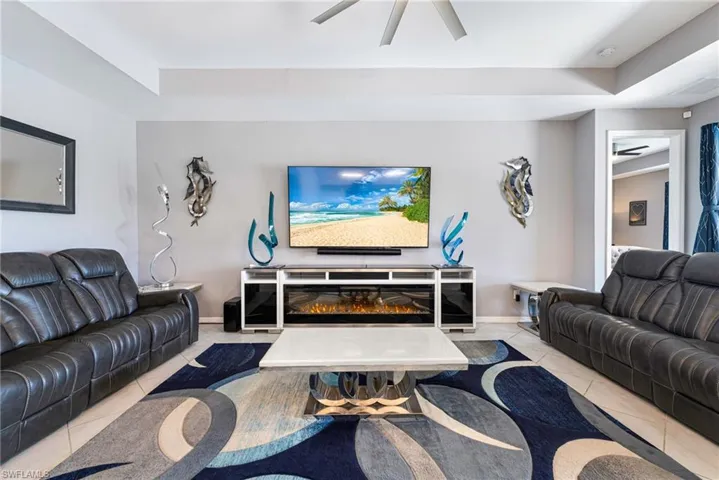 Living area featuring a multi-tiered ceiling, ceiling fan, and tile flooring