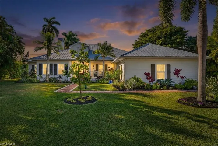 View of front of property featuring a metal roof and a yard