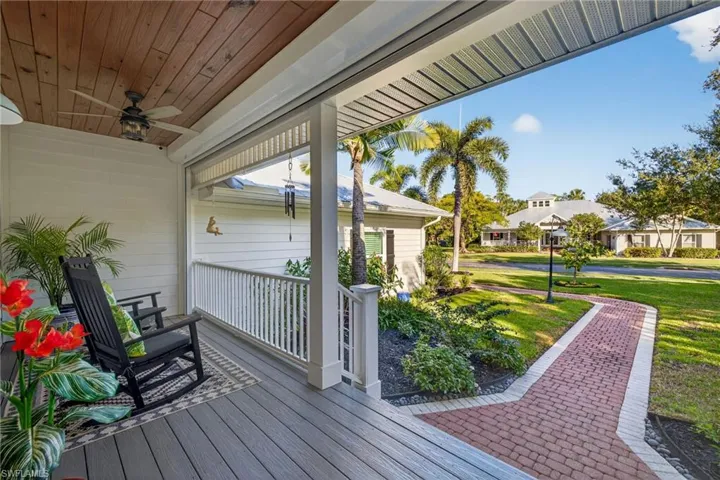 Wooden porch featuring a ceiling fan, a lawn, and a residential view