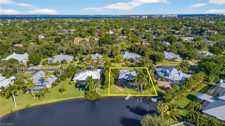 Aerial perspective of suburban area with a large body of water and property boundaries highlighted
