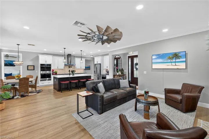 Living room with ornamental molding, ceiling fan, light wood finished floors, and recessed lighting