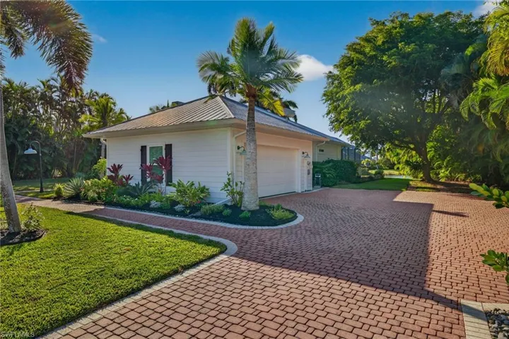 View of side of home with an attached garage, a yard, decorative driveway, and a metal roof