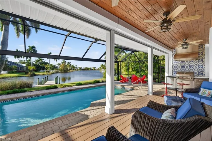 Swimming pool with screen enclosure, a grill, a sunroom, a deck with water view, and a patio area