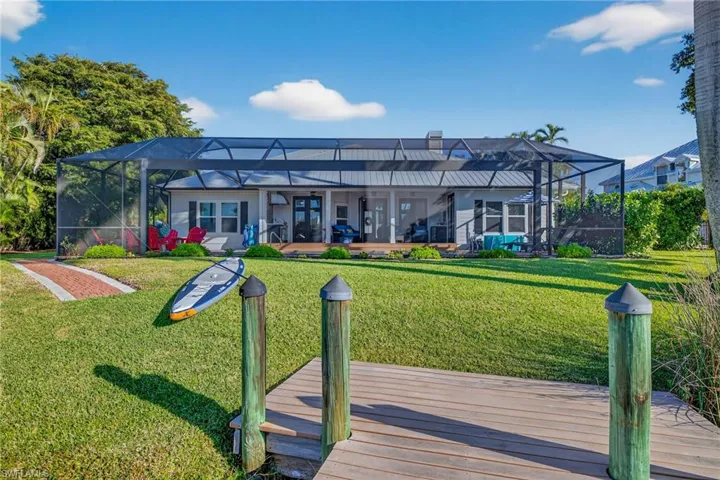 Rear view of property featuring screen enclosure, and a yard