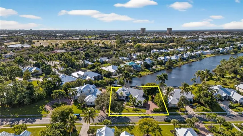 Aerial perspective of suburban area featuring property parcel outlined and a nearby body of water