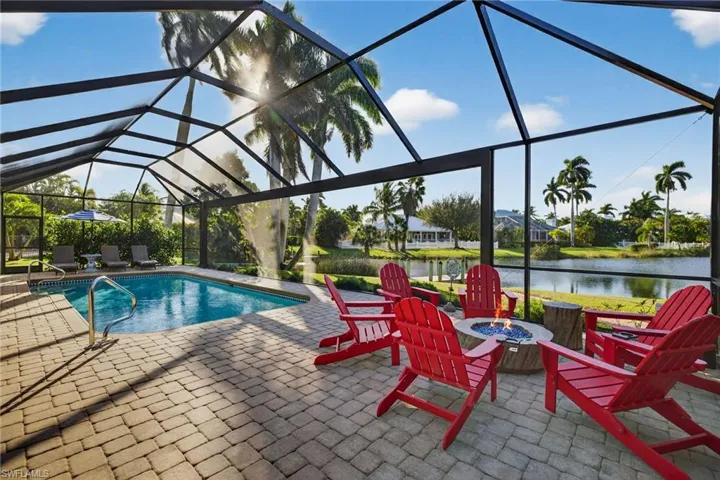 Outdoor pool screen enclosure, a patio area, a water view, and an outdoor fire pit